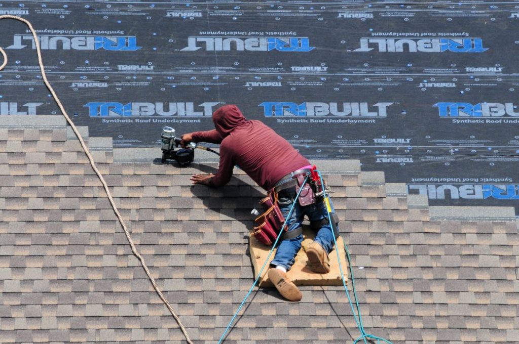 roofer installing new shingles on top of a synthetic roof underlayment, Wayzata